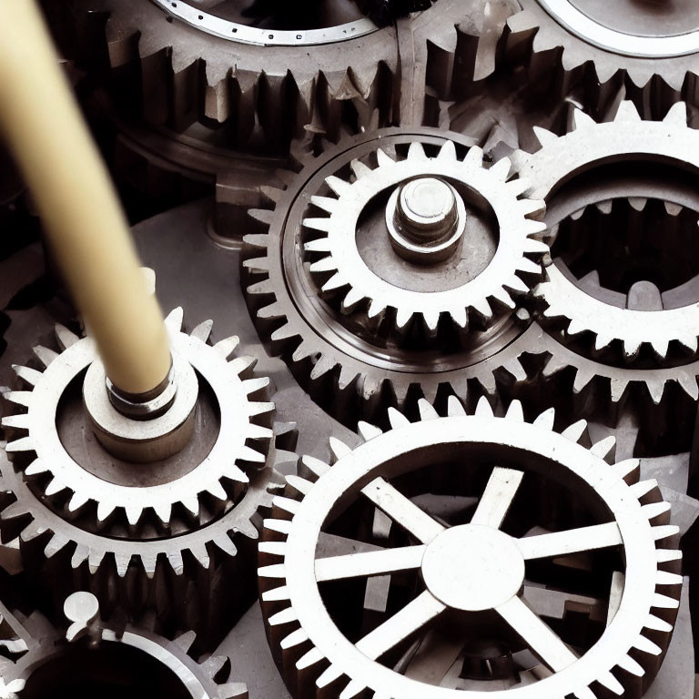 Detailed view of interconnected metallic gears and cogs with varying sizes and intricate teeth design.