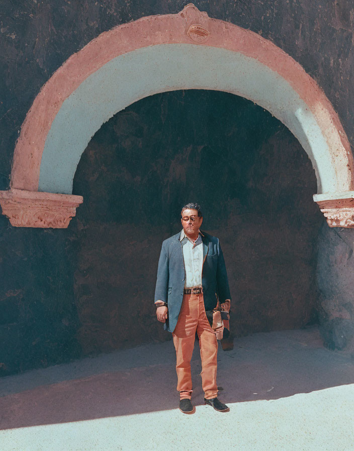 Confident man in blue blazer under weathered pink archway