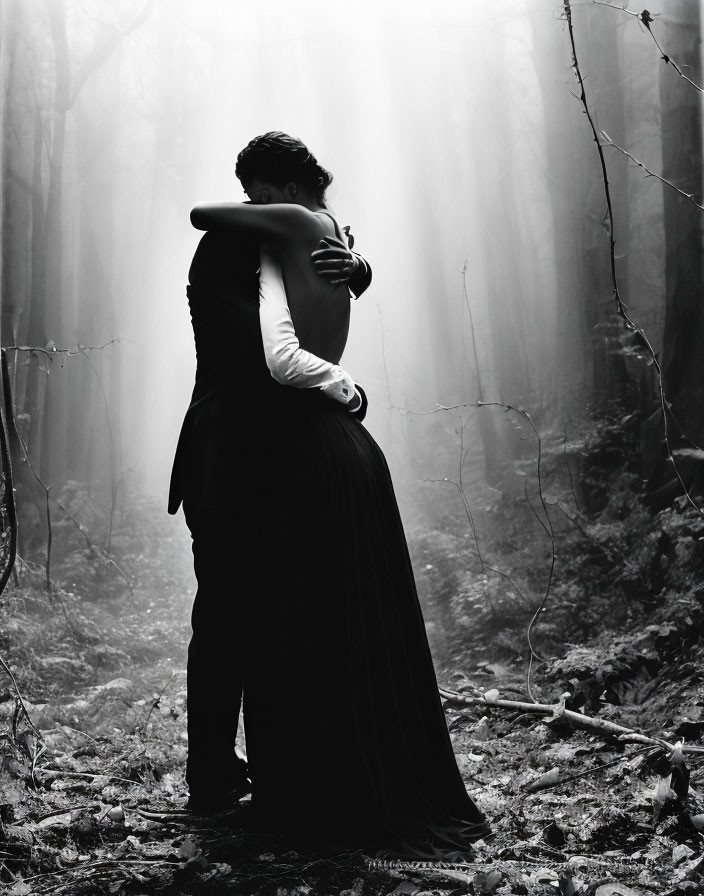 Embracing couple in misty forest with soft light.