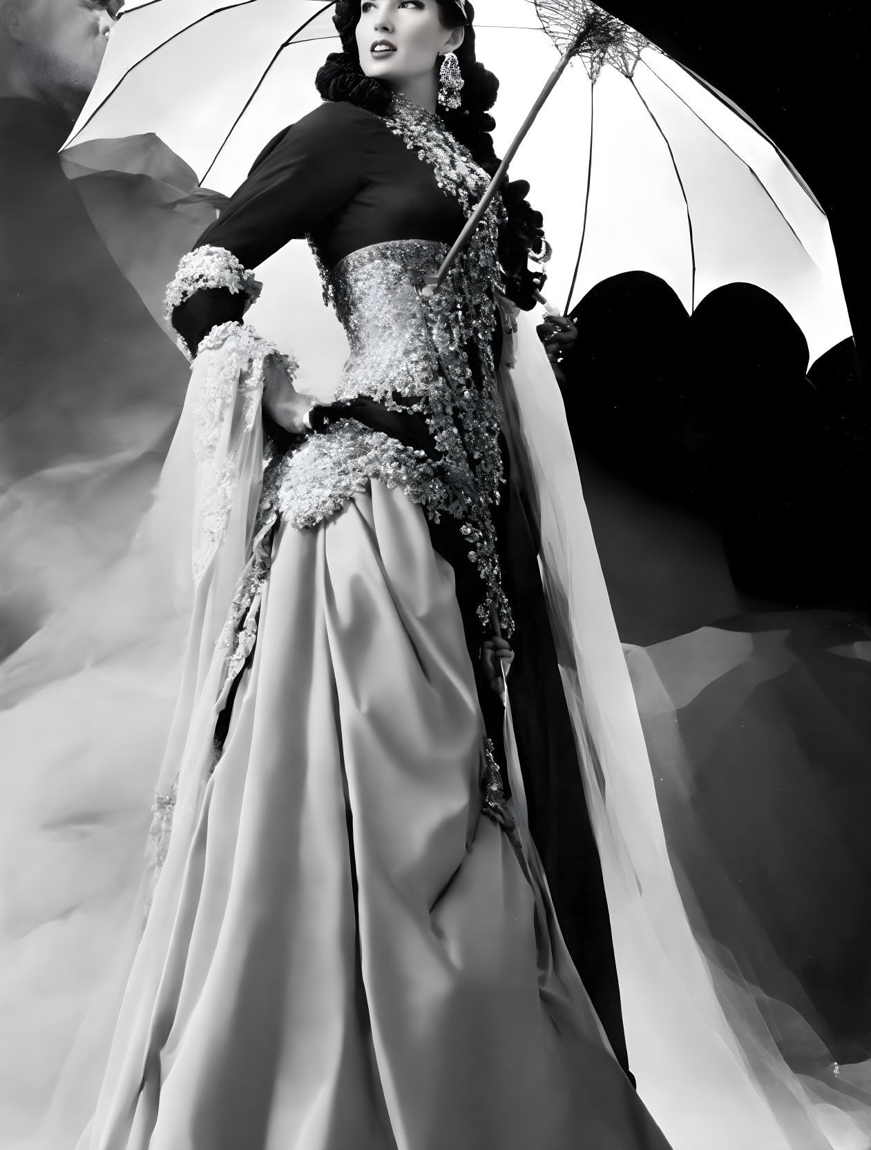 Vintage-style black and white photo of elegant model in ornate gown with lace parasol