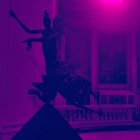 Dynamic sculpture silhouette against purple backdrop with classical elements