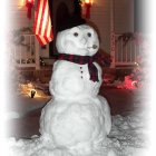 Snowman with top hat, red scarf, and carrot nose in snowy scene