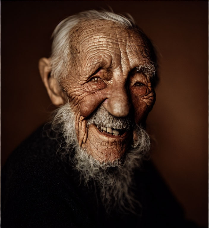 Elderly man with white beard smiling on dark brown background