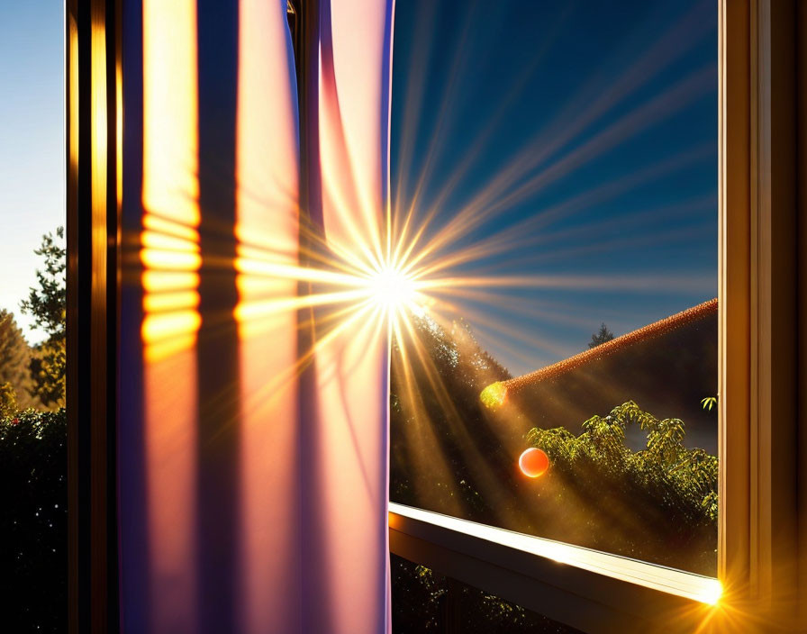 Sunrise with sunbeams through a window illuminating trees and a roof.