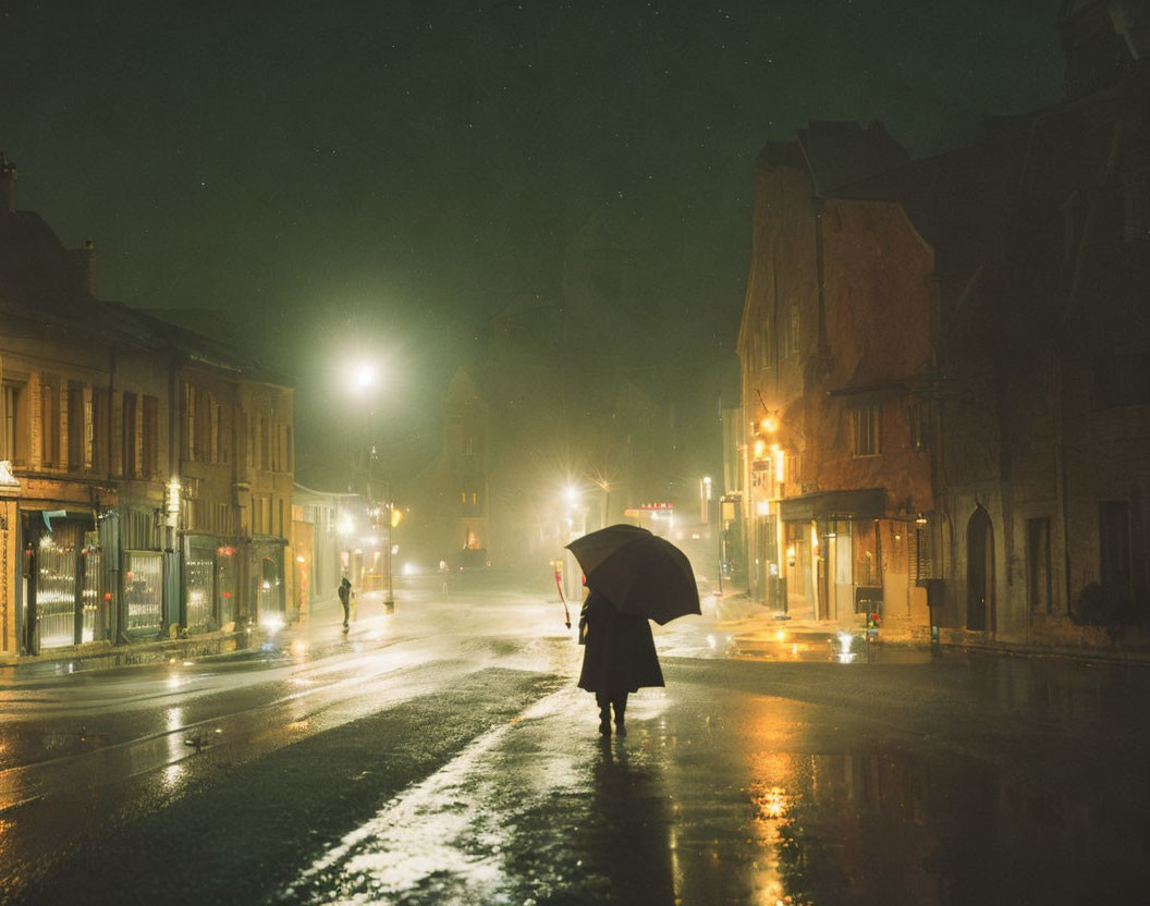 Solitary figure with umbrella on rain-slicked street at night