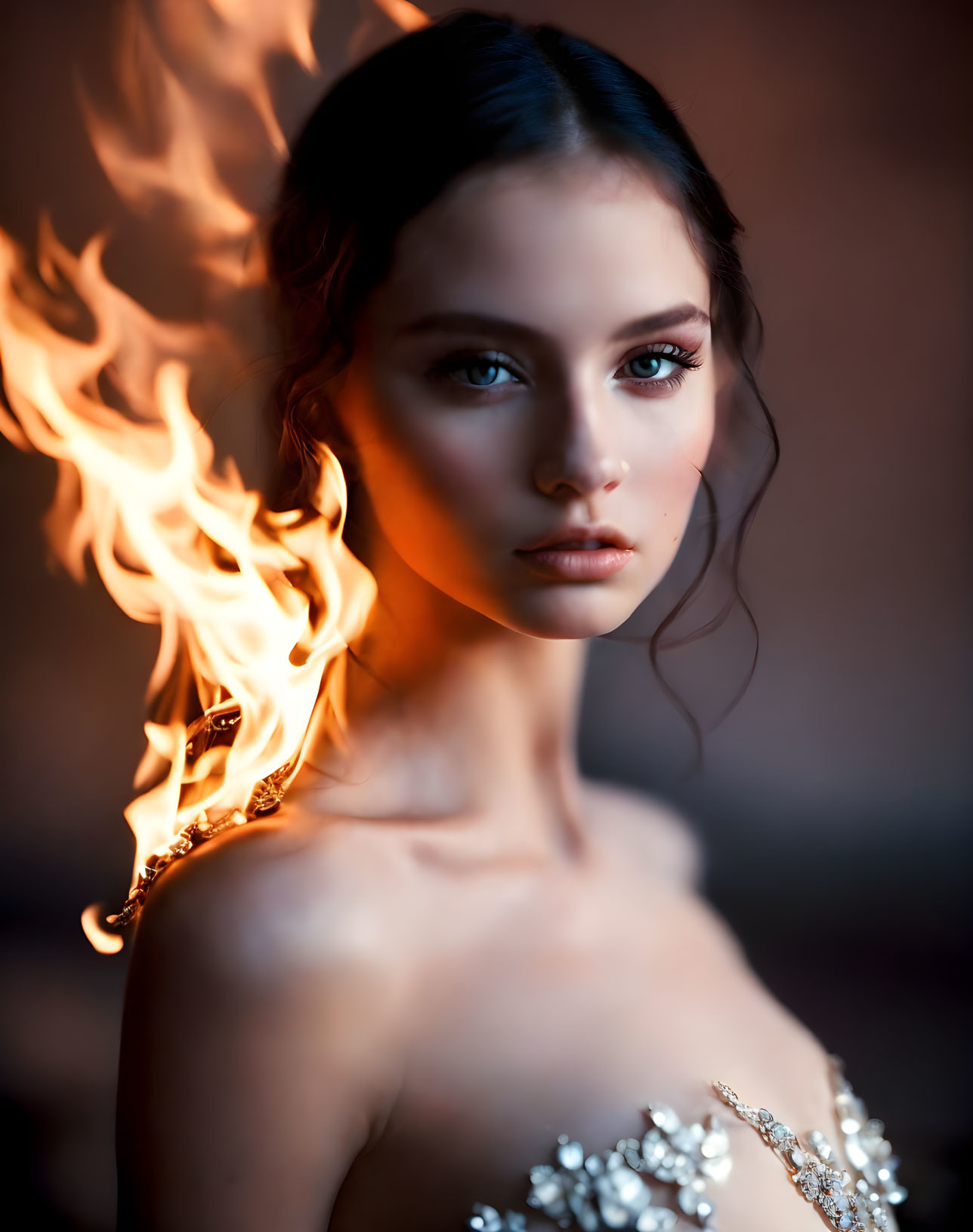 Striking woman with intense gaze and flame on shoulder in blurred background