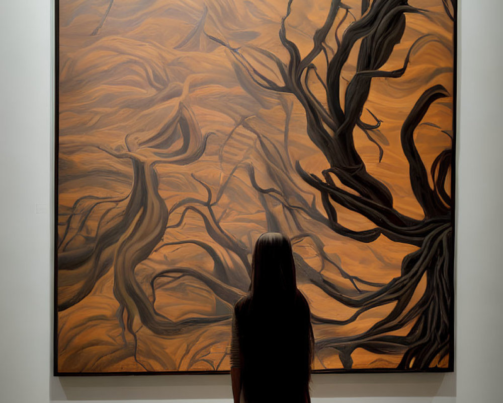 Long-haired person in front of swirling abstract painting with gnarled branches.