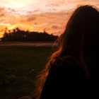 Silhouetted person on distant hilltop under dramatic red sky observed by foreground figure.