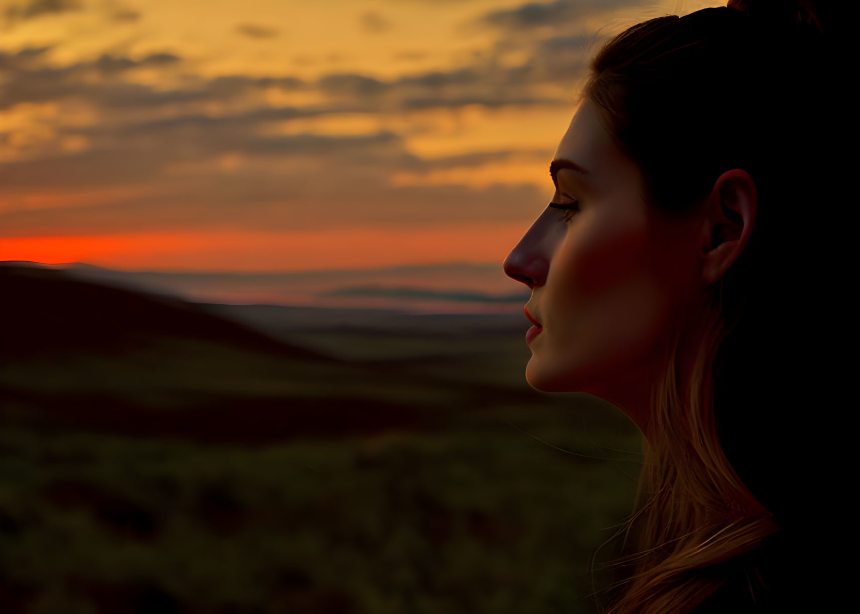 Profile of woman at sunset with warm hues casting soft light.