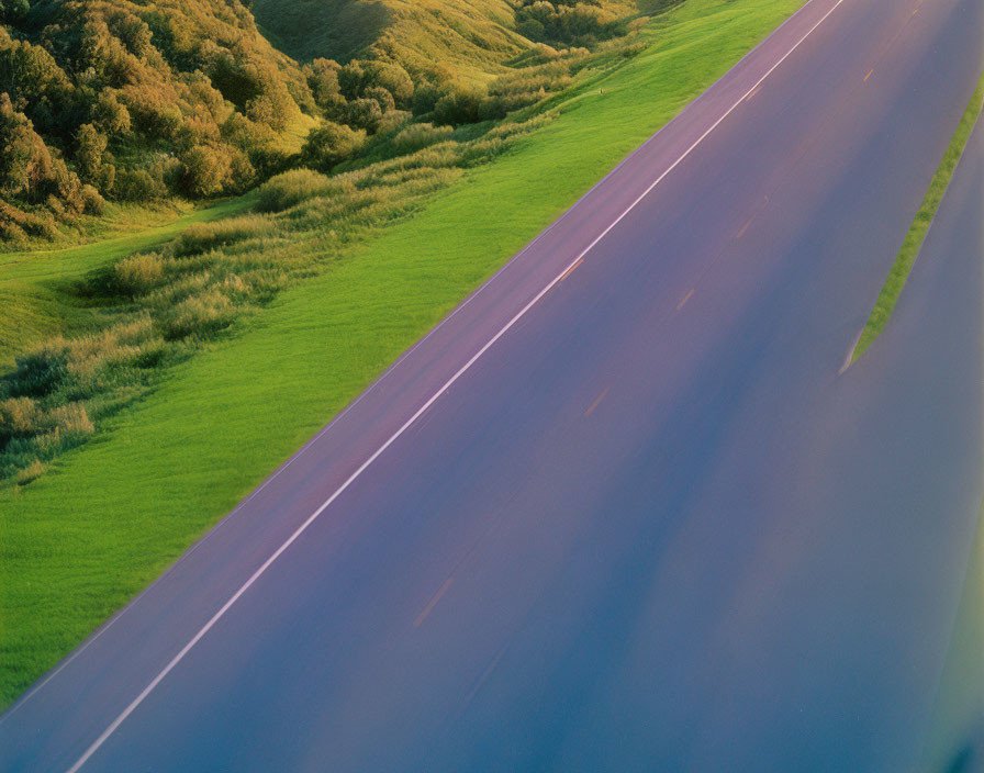 Blurred motion on empty highway through green fields