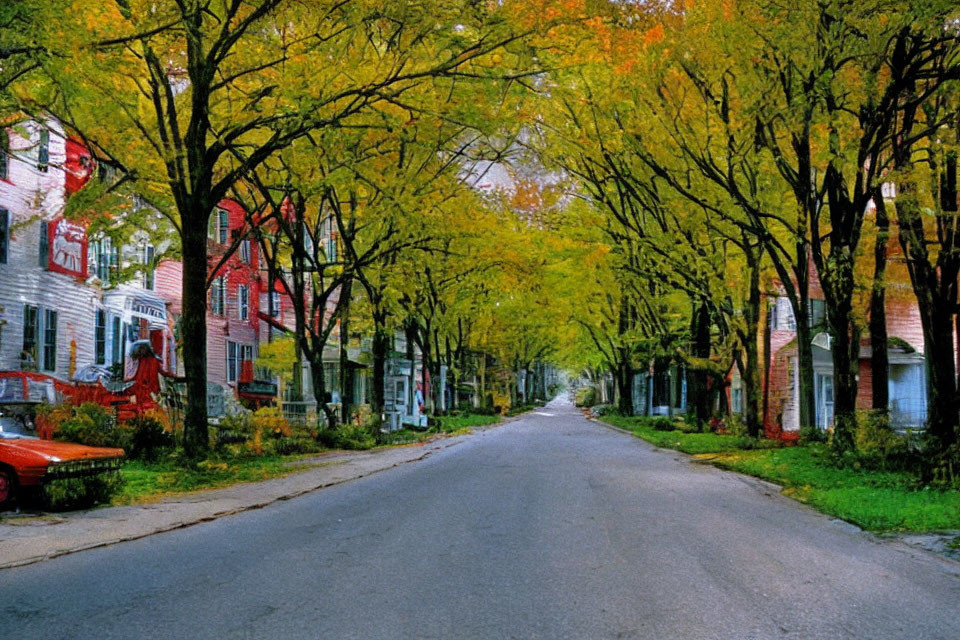 Colorful houses and autumn trees on quaint street with red car, cloudy sky