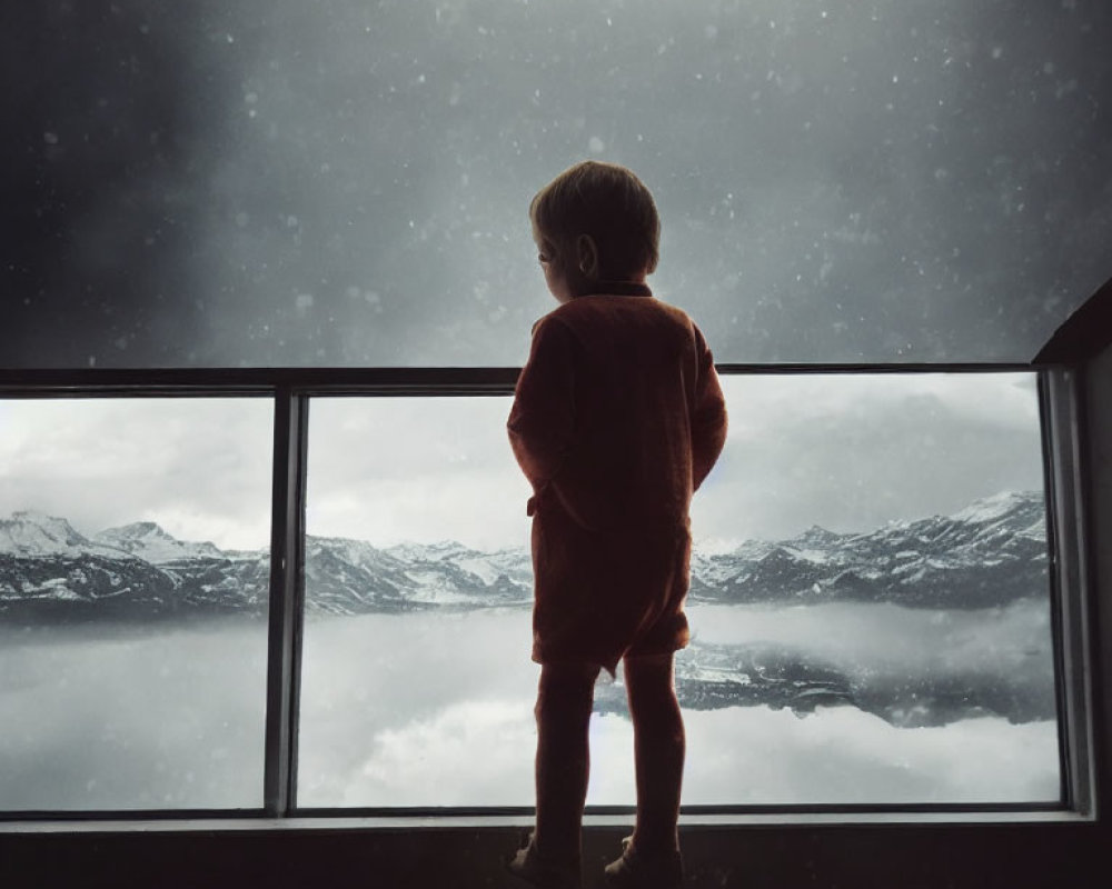 Child in red outfit gazes at snowy mountain through window