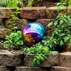 Colorful iridescent bubble in vibrant garden with purple, red, and green flowers