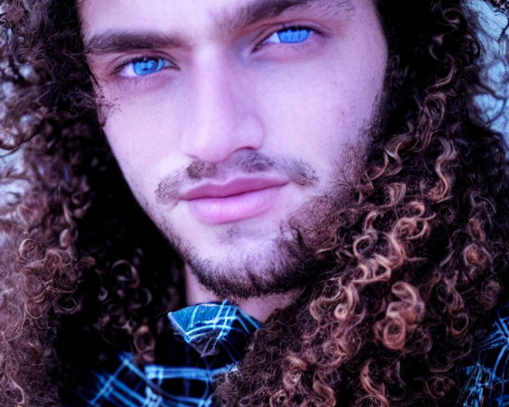 Close-up portrait of person with curly hair and blue eyes in checkered shirt