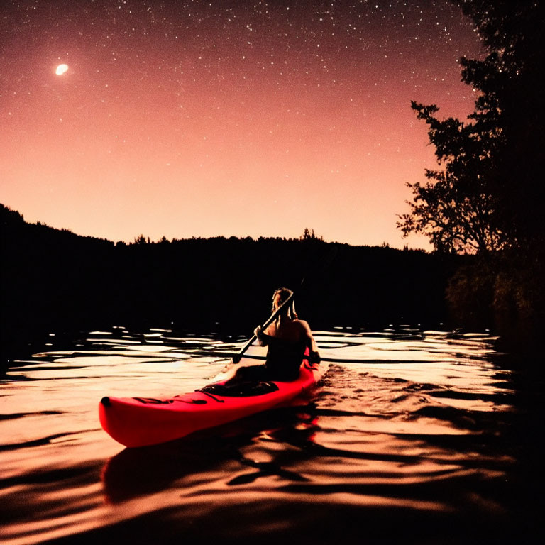 Night kayaking on calm lake under starry sky with crescent moon