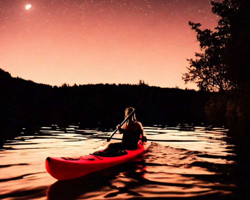 Night kayaking on calm lake under starry sky with crescent moon