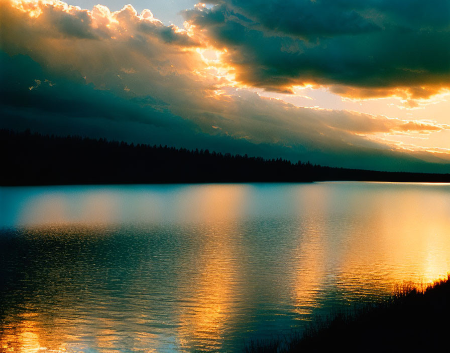 Tranquil lake at sunset with vibrant reflections and dark treeline