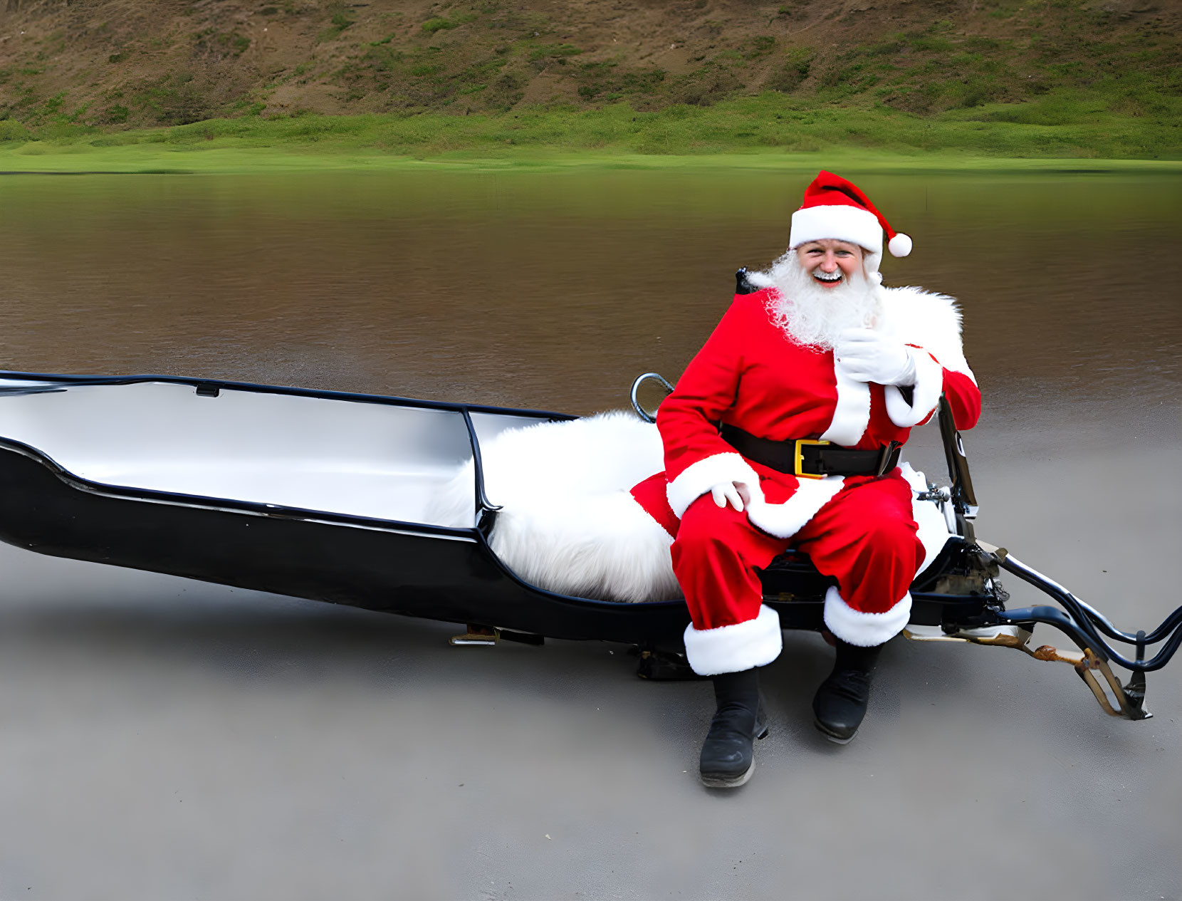 Santa Claus in modern sleigh on sandy area with hill and lake