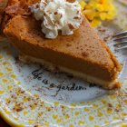 Watercolor painting of pumpkin pie slice with whipped cream, autumn leaves, and berries.