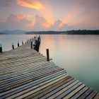 Serene lakeside sunset scene with boat at wooden jetty