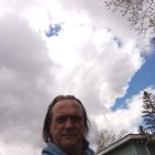 Serene man with white horse under halo in cloud backdrop