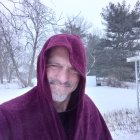 Person with Nest on Head and Bird in Purple Cloth Against Snowy Trees