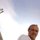 Man with Long Brown Hair and Beard in White Robe Gazing at Ethereal Clouds