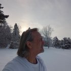 Serene man with long gray hair and lion in white robes under dramatic sky