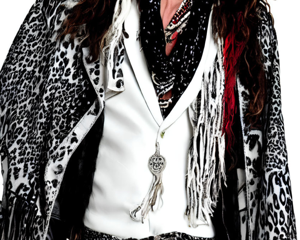 Long wavy hair person in white shirt and leopard print coat with layered necklaces and belt.