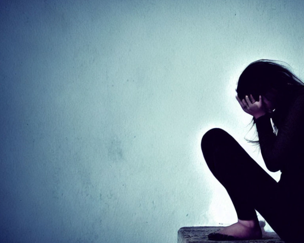 Distressed person sitting against plain background