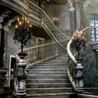 Luxurious interior with opulent staircase, gold railings, chandeliers, and warm lighting