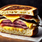 Multi-layered grilled cheese sandwich with ham and chocolate cookies on wooden background.