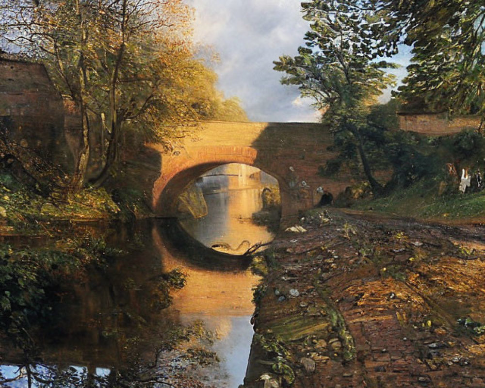 Stone bridge over calm river with autumn trees and brick pathway at sunset