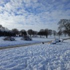 Snowy Winter Landscape with Deer Crossing Field and Farm Buildings