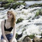 Woman in Blue Dress Poses by Sunlit Waterfall