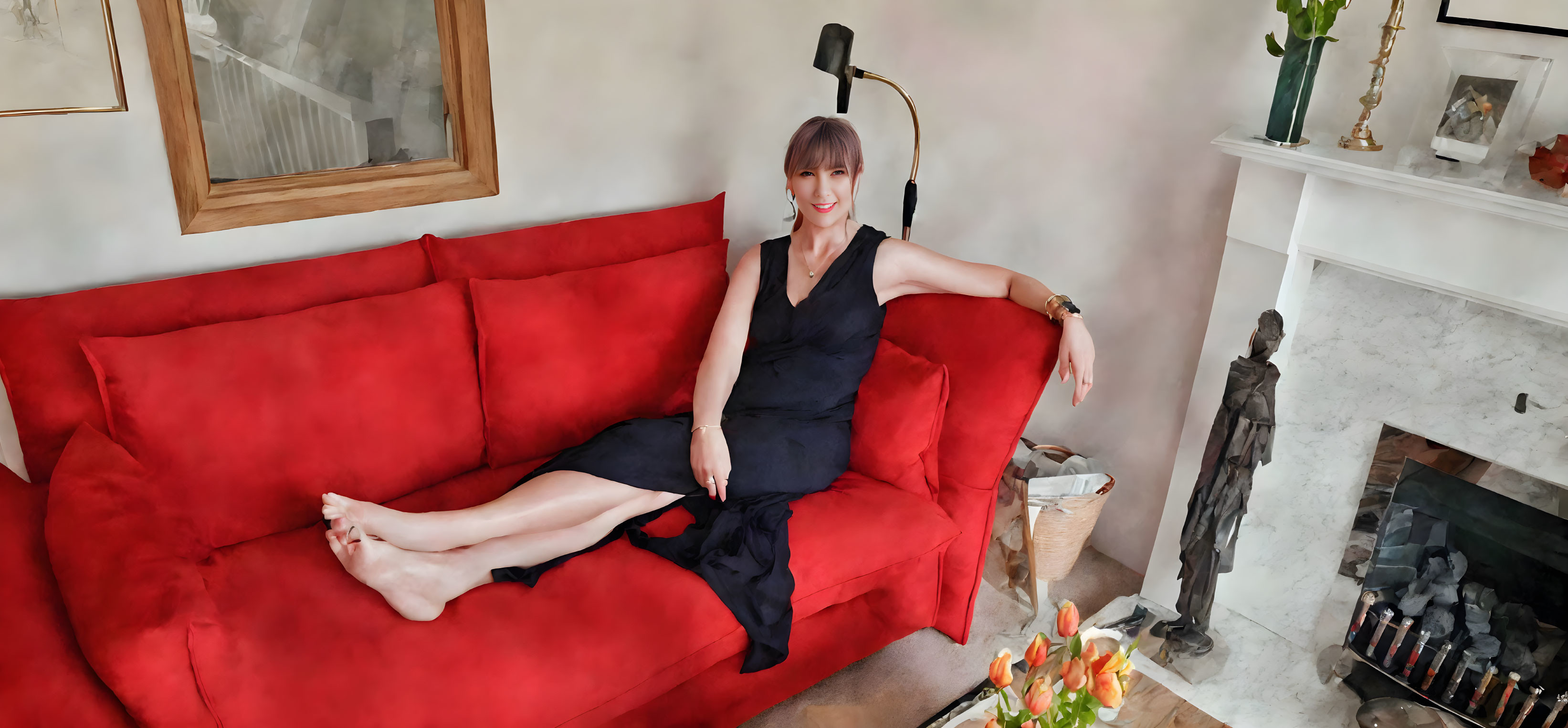 Smiling person on red couch in living room with fireplace and sculpture