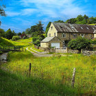 Tranquil rural scene with house, fences, trees, pastures, and mountains