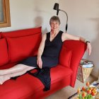 Smiling person on red couch in living room with fireplace and sculpture