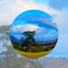 Surreal landscape with eucalyptus trees, hills, and mountains in transparent bubble