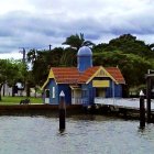 Tranquil painting of blue-roofed house by calm lake