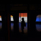 Silhouette of person by colorful mosaic window and trees