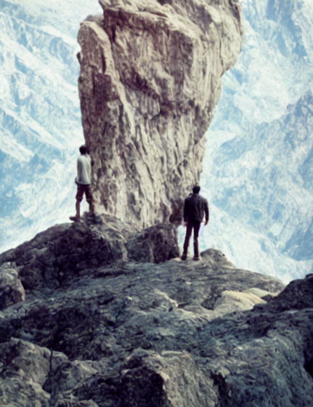 Explorers on rocky outcrop admire rugged mountain terrain