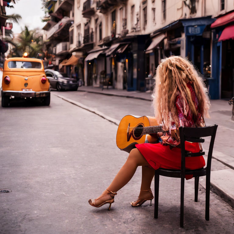 Woman with Guitar Sitting on Chair Near Vintage Car in Quaint Street