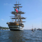 Tall ship with full sails in stormy seas with red flag