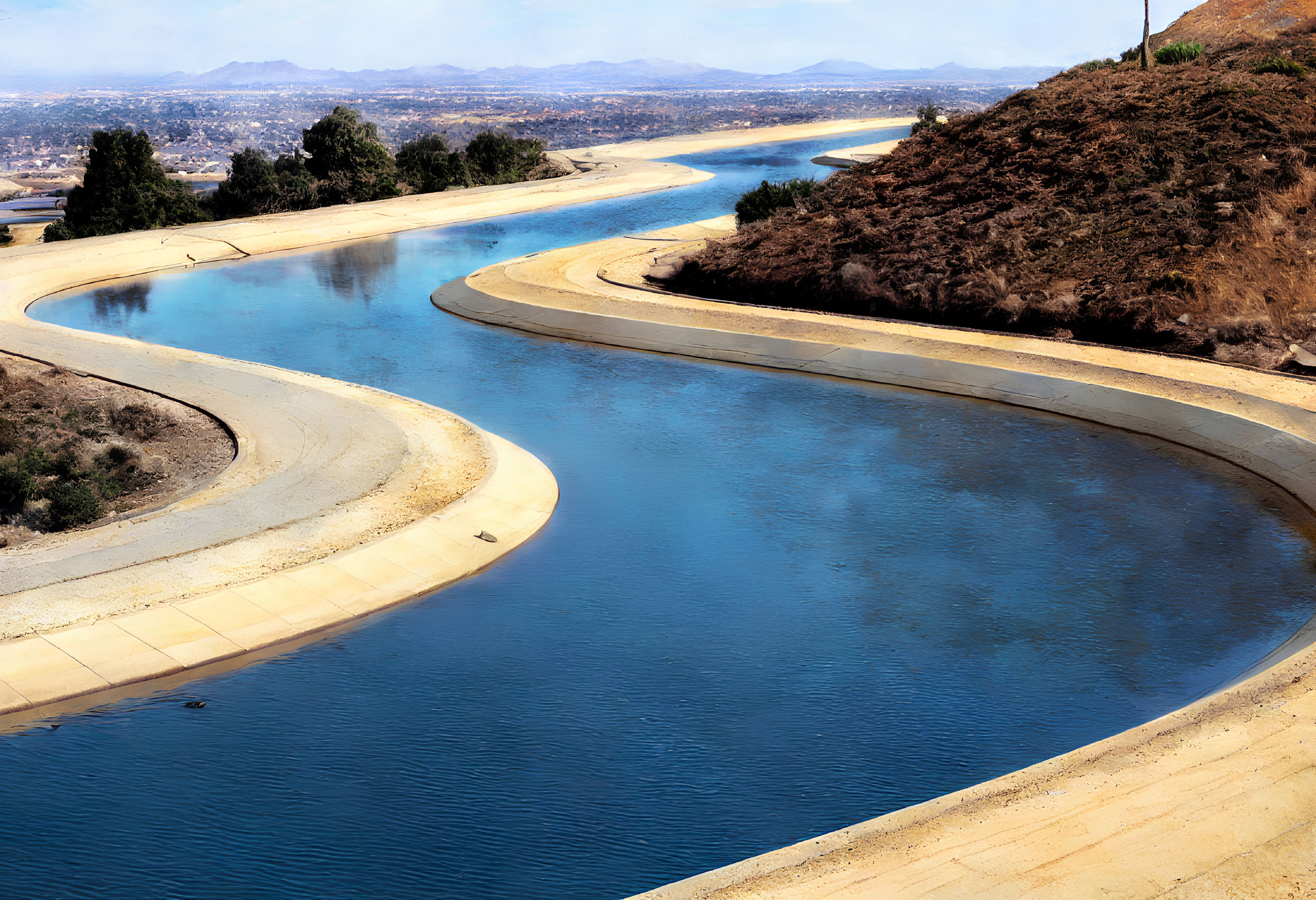 Artificial Water Channel in Dry Hilly Terrain with Cityscape View