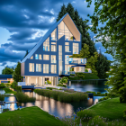 Tranquil stream setting: Idyllic A-frame house with greenery, lit up at dusk