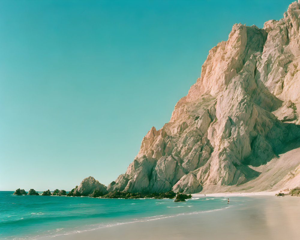 Tranquil Beach Scene with Clear Water, Sandy Shore, and Rugged Cliff