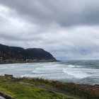 Scenic coastal landscape with cliffs, hills, wildflowers, and crashing waves