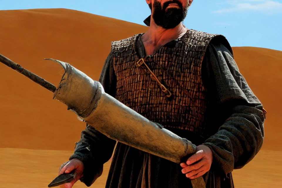 Man in historical garb with metal horn in desert.