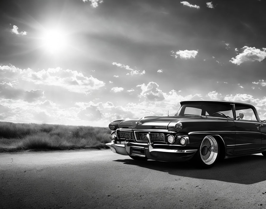 Vintage Black Car Parked on Empty Road Under Sunny Sky and Clouds Above Expansive Field